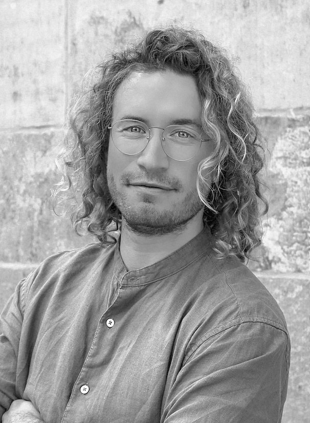 Phillip Nalesny, Autor von „Die Agilistin“, vor einer Sandsteinmauer, schwarzweiß